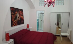 A bedroom with a large bed, a wardrobe, a shower, and a red artwork on the wall. - B&B Garibaldi (Alcamo)