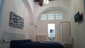 A bedroom with a bed, a painting, a TV, and a window with a view. - B&B Garibaldi (Alcamo)