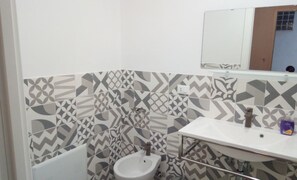 A bathroom with a white sink, a bidet, and a mirror above the sink. - B&B Garibaldi (Alcamo)