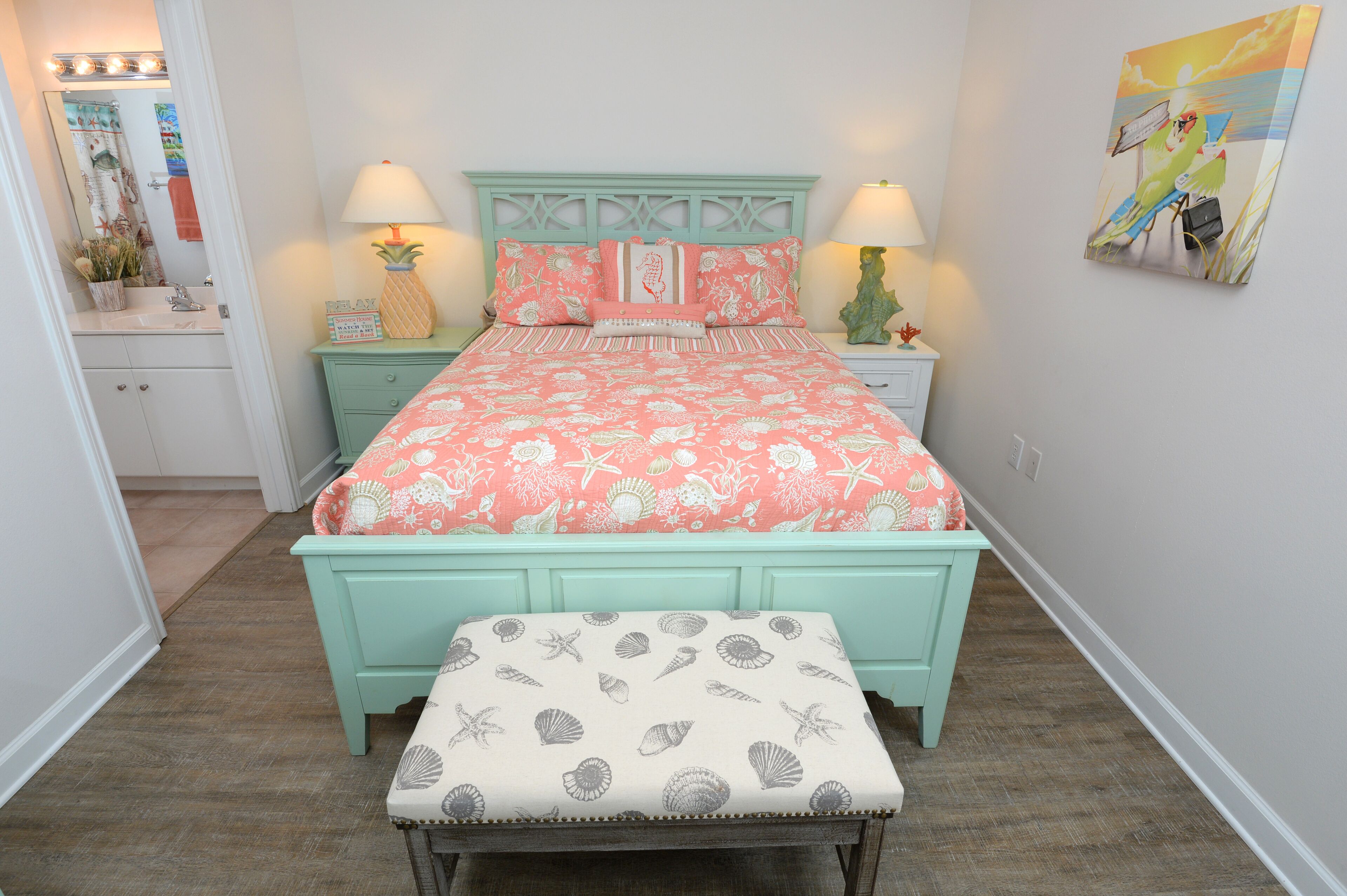 A bedroom with a bed, nightstands, a bench, and a wall with a painting.