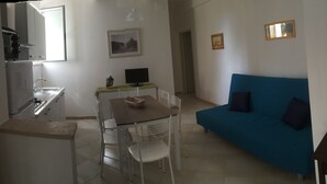 Um espaço compacto com cozinha compacta, área de refeições e sofá azul.