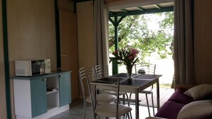A compact room with a dining table, chairs, a microwave, and a small cabinet.