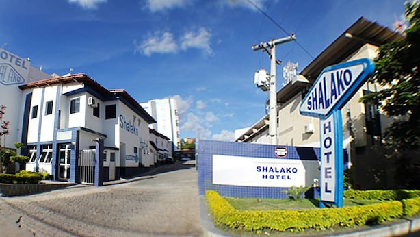 A hotel entrance with a sign reading "Shalako Hotel" and a blue sign indicating the hotel's name. - Shalako Hotel (Vitoria da Conquista)
