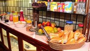 A buffet with various food items, including fruits, bread, and condiments. - Shalako Hotel (Vitoria da Conquista)