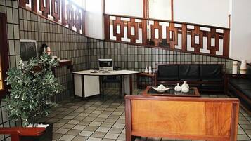 A traditional Japanese-style room with a tatami mat floor, a low wooden table, a black leather sofa, and a decorative wooden partition.