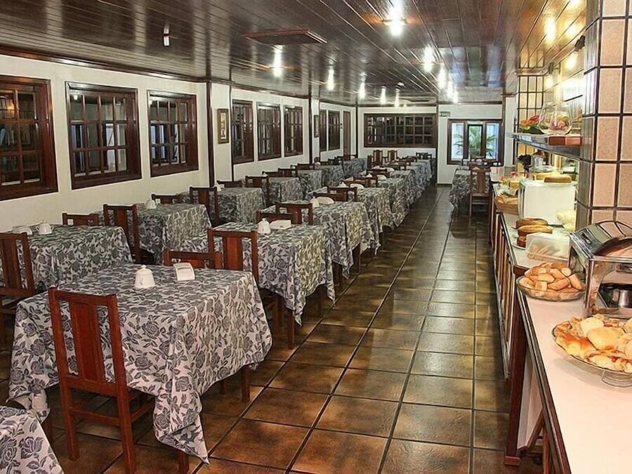 A restaurant with multiple tables and chairs, a buffet area with food items, and a tiled floor.
