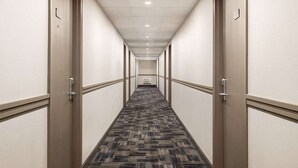 A hotel hallway with carpeted floors, beige walls, and doors on both sides. - Super 8 by Wyndham SARNIA (Sarnia)