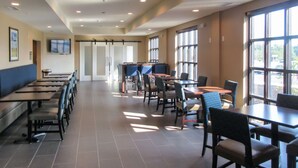 A spacious dining area with long tables and chairs, large windows providing natural light, and a television mounted on the wall. - Comfort Inn & Suites Gap Amish Country (Gap)