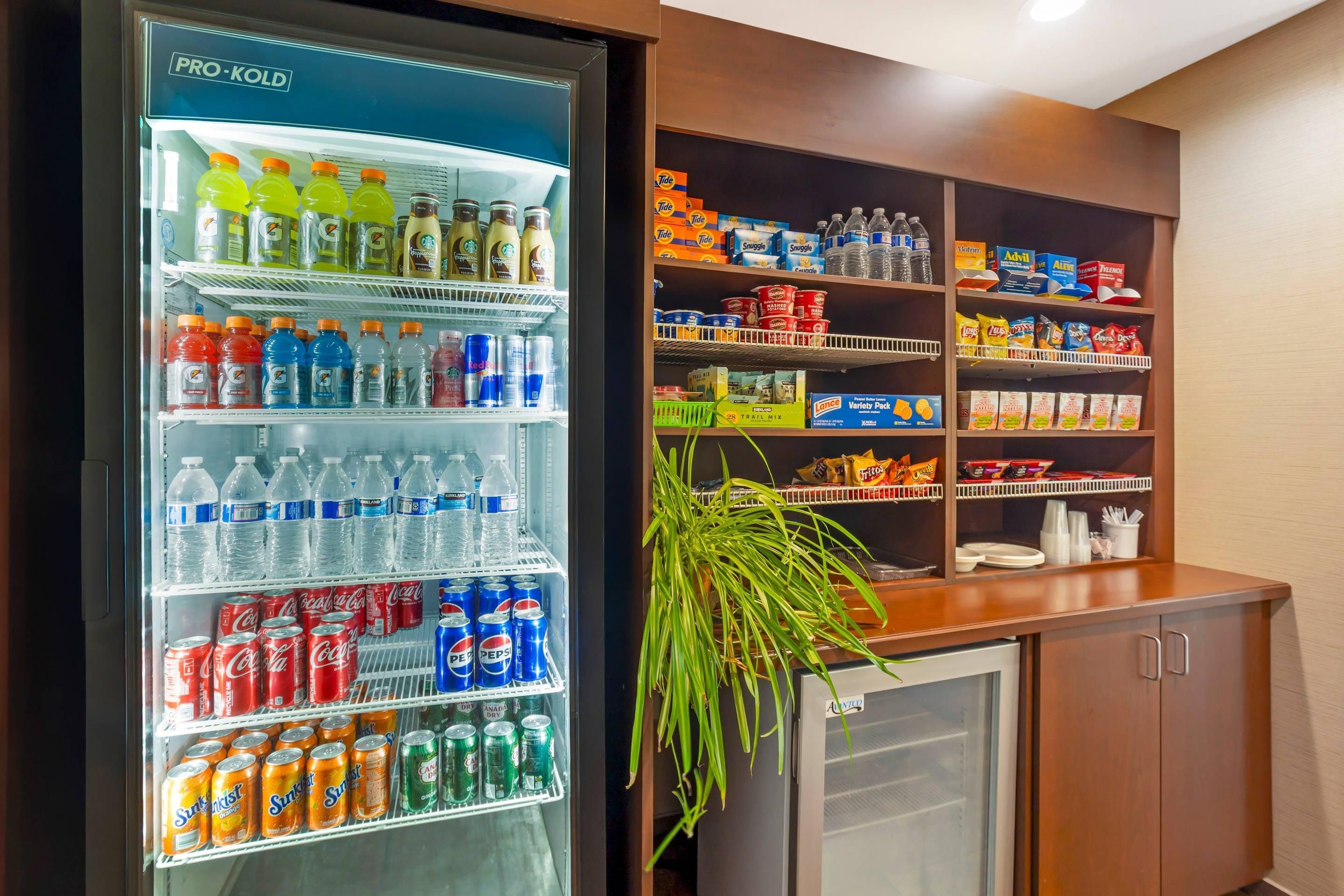 A Pro-Kold refrigerator stocked with various beverages and a shelf unit with snacks and bottled water.