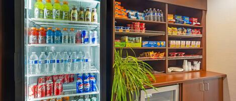 A Pro-Kold refrigerator stocked with various beverages and a shelf unit with snacks and bottled water.