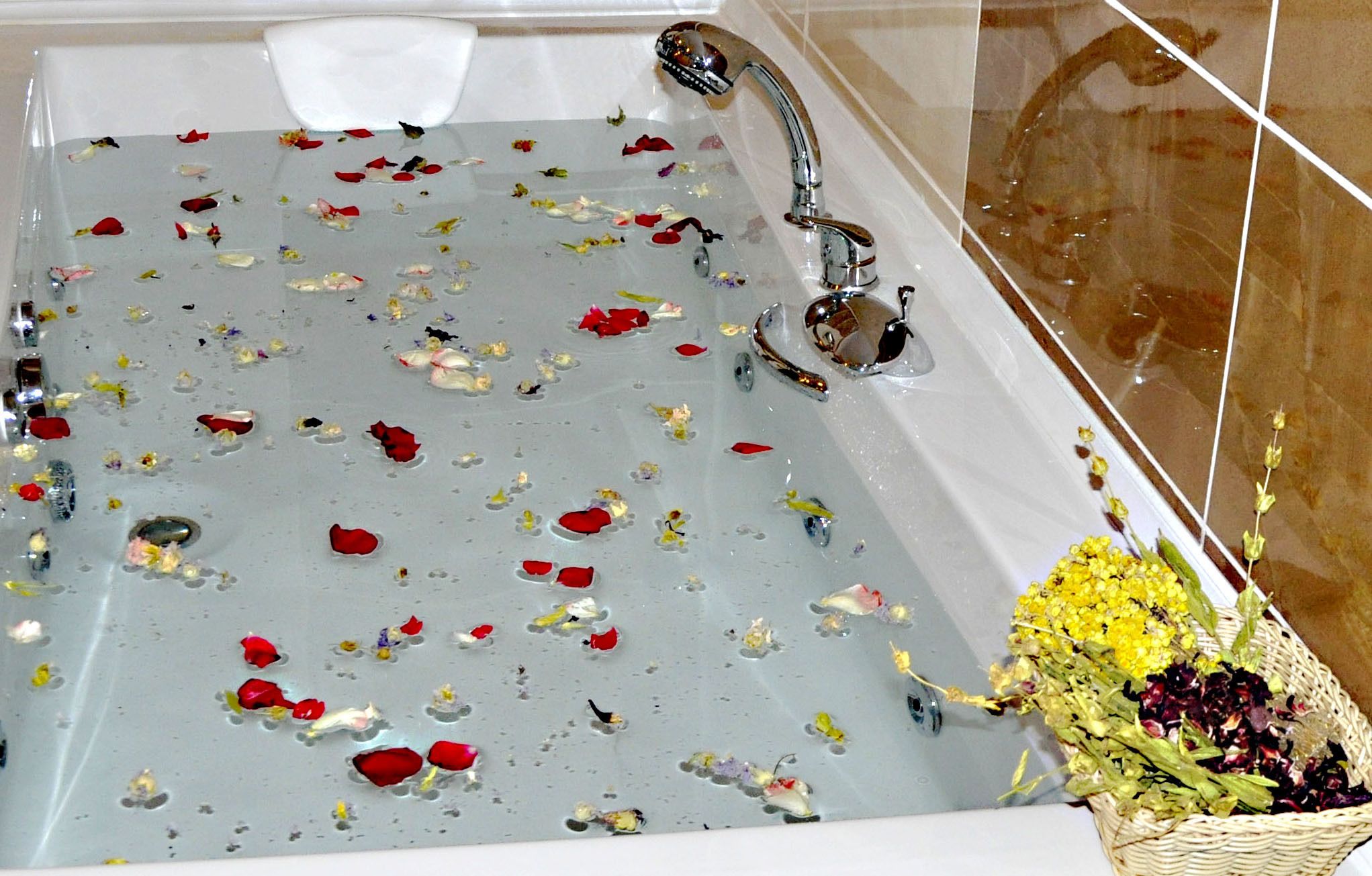 Una bañera llena de pétalos de rosa y una cesta de flores.