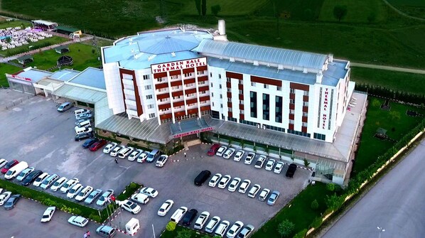 Un hotel grande con un letrero llamativo, varios estacionamientos y un patio central.