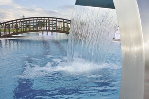 Una fuente de agua con un puente al fondo.