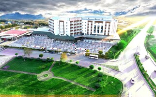 Un hotel de varios pisos con un amplio estacionamiento, un patio central y vistas del paisaje circundante.