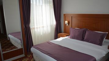 A hotel room with a large bed, a wooden headboard, a nightstand, and a mirror.