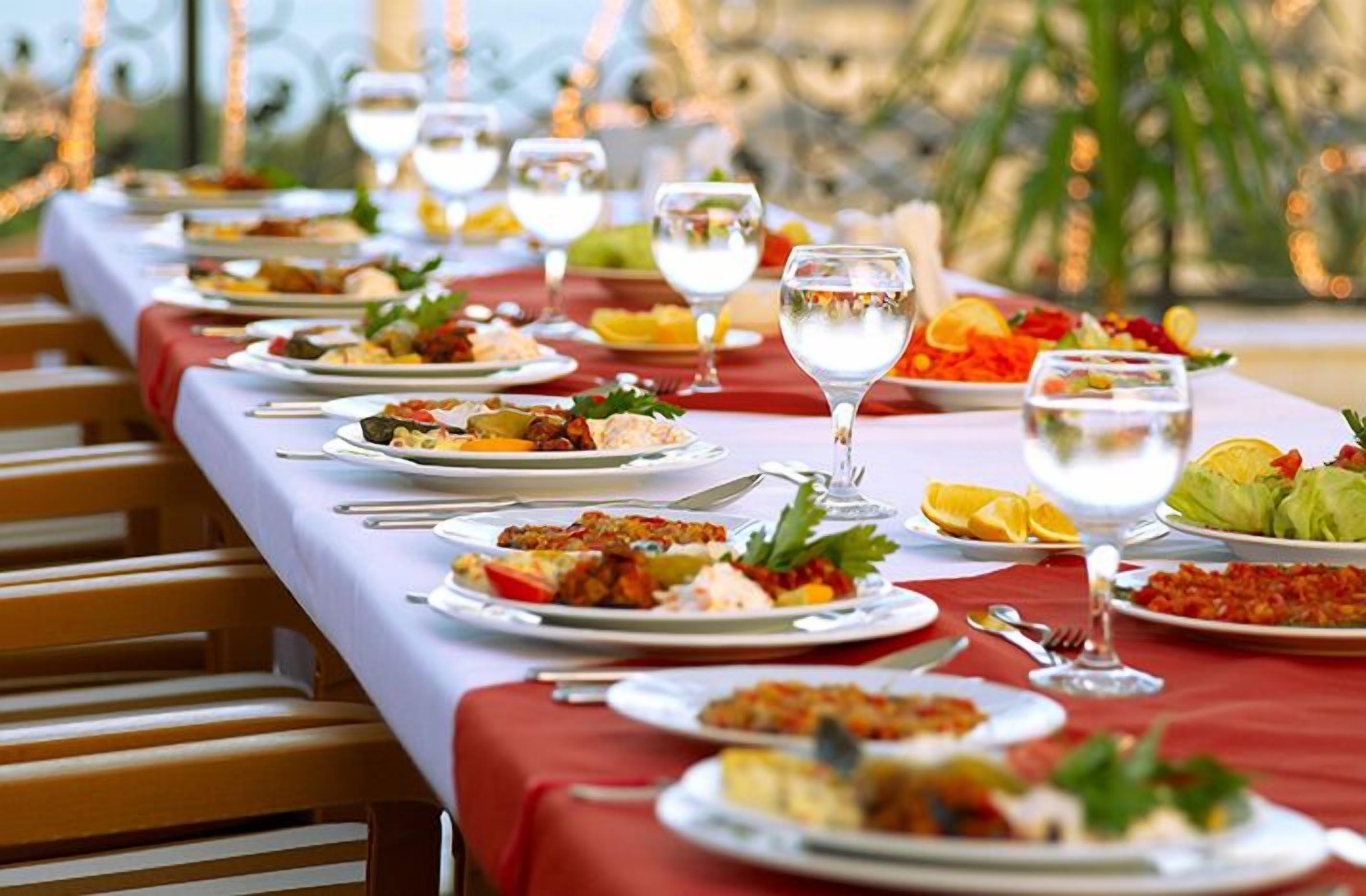 A long dining table set with various dishes and glasses, likely in a restaurant or banquet hall.