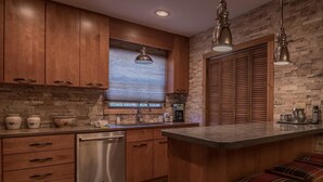 A kitchen with wooden cabinets, a stone backsplash, and a built-in dishwasher.