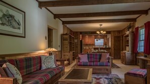 A cozy, rustic living room with a plaid sofa, a wooden coffee table, and a patterned rug.