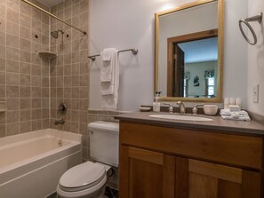 A bathroom with a bathtub, toilet, sink, and a large mirror.