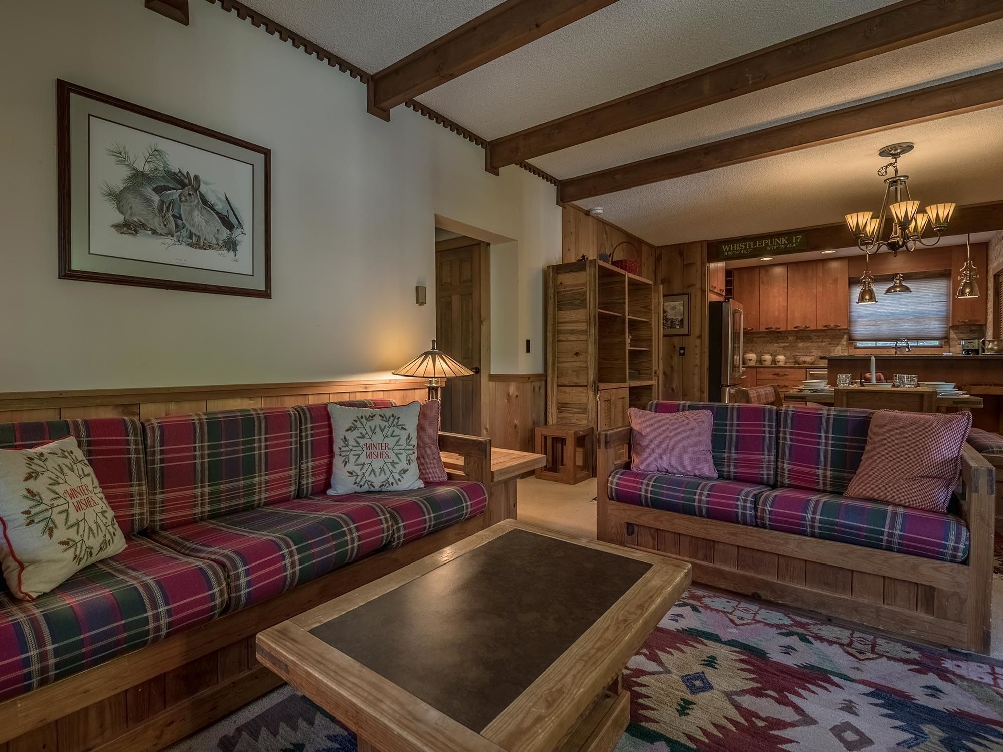 A cozy living room with plaid sofas, a coffee table, and a fireplace.