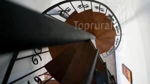 Un escalier en colimaçon, doté d’une rampe et orné d’un motif circulaire sur le mur.