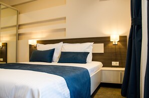 A hotel room with a large bed, two bedside tables, a nightstand, a mirror, and a wall-mounted lamp. - milano blue (Constanta)