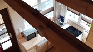 A kitchen with wooden beams, a dishwasher, and a window overlooking a garden. - Sunny holiday home with a cozy sleeping loft, idyllically located in the garden. (Barth)
