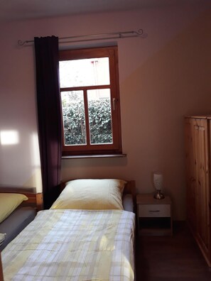 Cozy retreat with a single bed, bedside table, and window with a view.