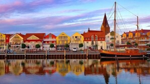 A waterfront with colorful buildings and a docked boat. - Sunny holiday home with a cozy sleeping loft, idyllically located in the garden. (Barth)