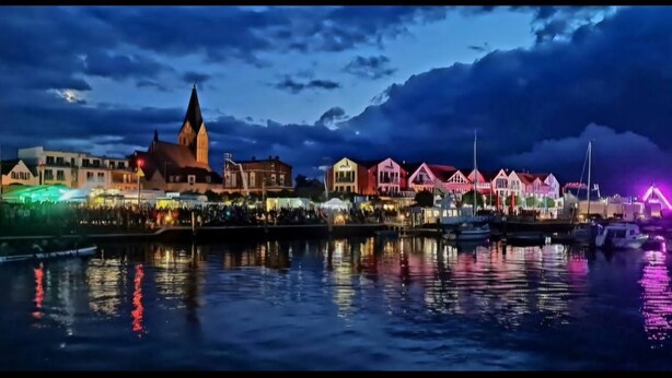 A waterfront cityscape with historic buildings and a prominent church tower. - Sunny holiday home with a cozy sleeping loft, idyllically located in the garden. (Barth)