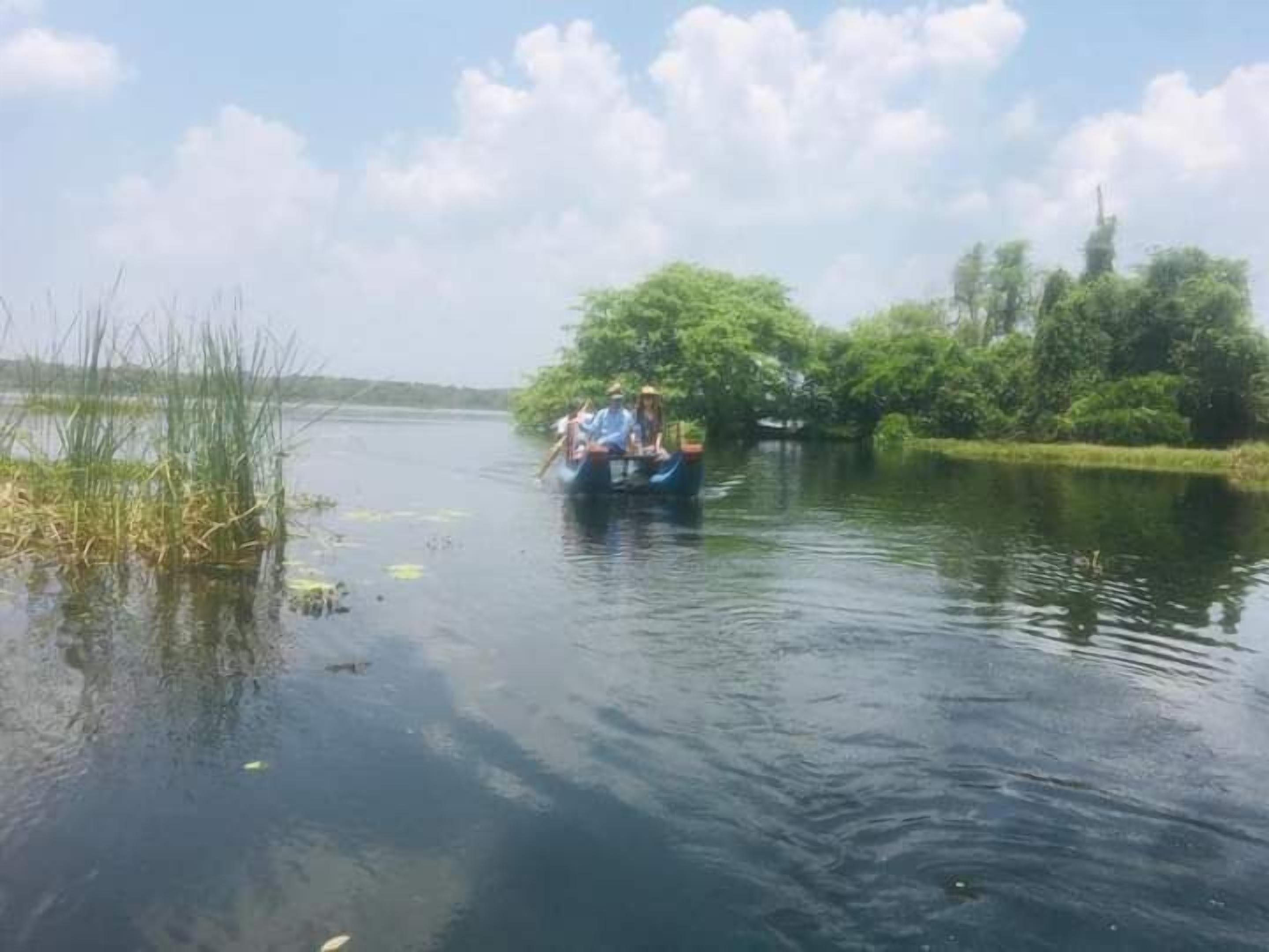 Un bateau sur une étendue d’eau calme, bordée de végétation.