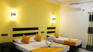 Une chambre d’hôtel avec deux lits, chacun doté d’une tête de lit noire et de linge de lit blanc. Deux lampes murales sont fixées de part et d’autre des lits, et un appareil de climatisation est installé au-dessus du lit situé à droite.