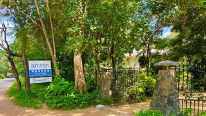 Une enseigne indiquant l’accès à l’Amron Resort, avec une liste des équipements disponibles, une entrée sécurisée et une végétation luxuriante.