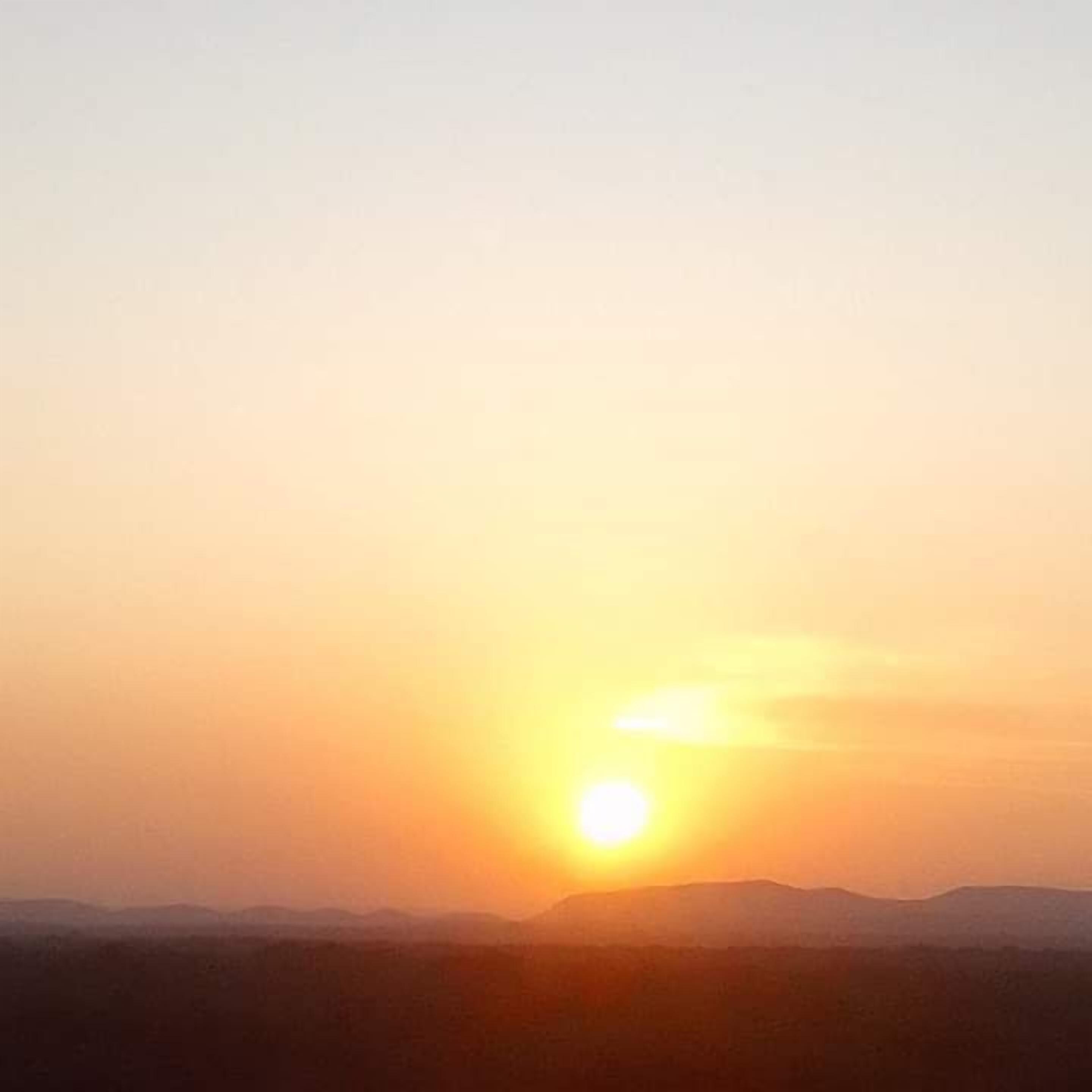 Ein Sonnenuntergang über einer gebirgigen Landschaft.