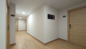 A hallway with wooden flooring, white walls, and doors numbered 206, 211, and 2.