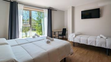 A hotel room with two beds, a desk, a chair, a TV, and a balcony with curtains.