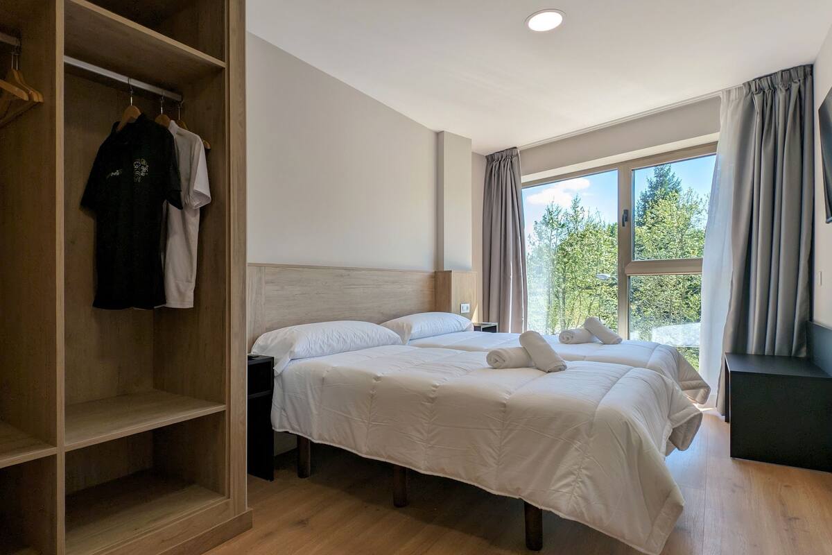 A hotel room with a large bed, a wardrobe, and a window with curtains.