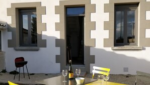 Un espace de restauration en plein air avec une table et des chaises jaunes, une bouteille de champagne et un saladier.