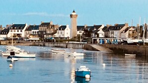 Un port avec des bateaux, un phare et des immeubles d’habitation le long de la rive.