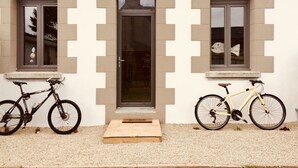Un bâtiment avec deux fenêtres et une porte, devant chacune desquelles est garé un vélo.