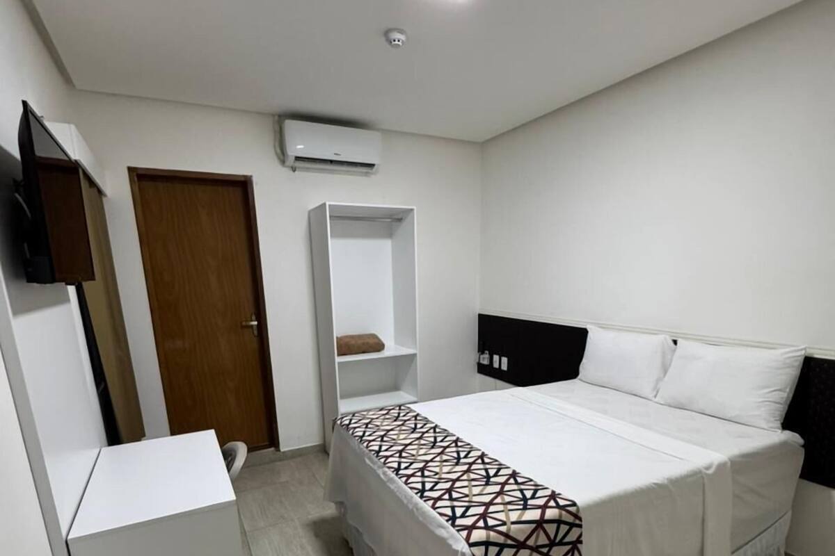Ein Schlafzimmer mit Bett, Kleiderschrank, Ablagefläche und einer Tür.