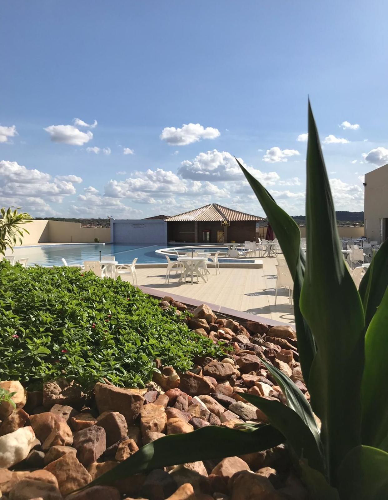 Área de piscina com espreguiçadeiras e um edifício ao fundo.