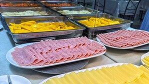 Un buffet proposant une variété de plats, notamment du jambon en tranches, du fromage jaune et d’autres plats préparés.