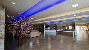 Un hall d’entrée spacieux comprenant un comptoir d’accueil, un espace détente et une grande plante en pot.