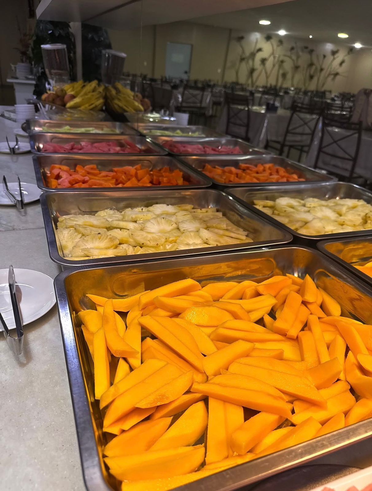 Un bufé con diversos alimentos, incluyendo piña, mango y zanahorias.