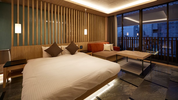A modern hotel room with a large bed, a sofa, a small table, and a balcony with a railing. - ALFIT HOTEL & BAR AKASAKA (Tokyo)