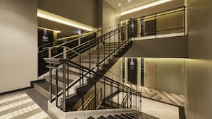A modern hotel interior with a multi-level staircase, a reception area, and a well-lit corridor. - ALFIT HOTEL & BAR AKASAKA (Tokyo)