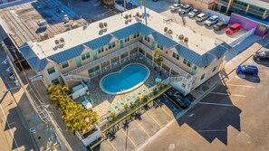 A hotel with a pool, outdoor seating, and a parking lot. - 🌴Steps to Sand @ Clearwater Beach Suites | Heated Pool • Split Floor Plan ➠ CBS 206 (Clearwater Beach)