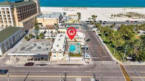 A hotel with a swimming pool, parking lot, and beach view. - 🌴Steps to Sand @ Clearwater Beach Suites | Heated Pool • Split Floor Plan ➠ CBS 206 (Clearwater Beach)