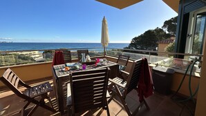 A balcony with a table, chairs, and a view of the sea.